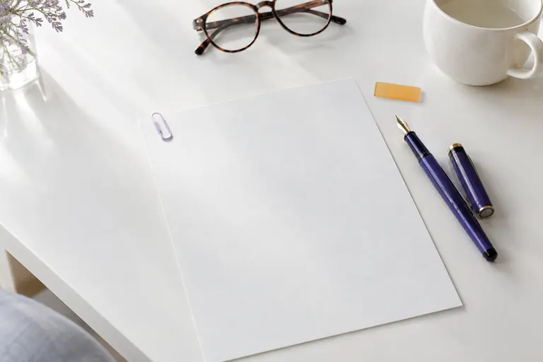 Bureau blanc minimaliste avec feuille vierge, stylo violet et lunettes, ambiance de profil professionnel